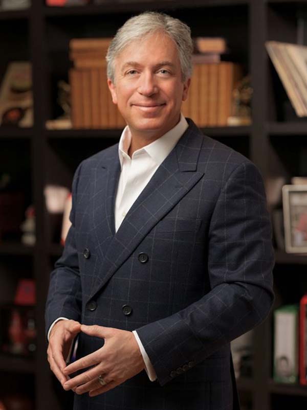 Man in suit standing before bookshelf.