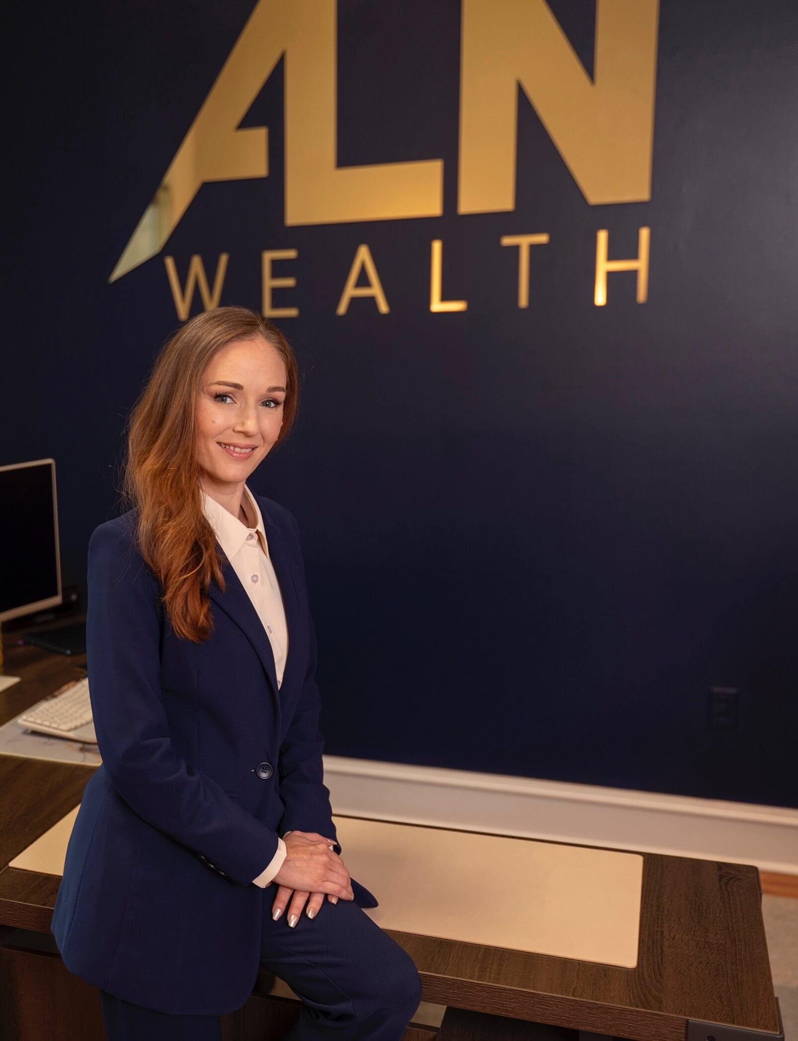 A professional woman in a navy blazer smiling at a wealth management office.